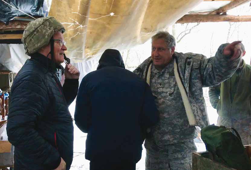 Feb19Web7 Army Chaplain Albert (center) was our guide in the war zone. Hannu tries on a soldier's heavy head gear, and not very comfortable. The Apostle Paul says: "Take the helmet od salvation and the sword of the Spirit..." Ef.6:17.