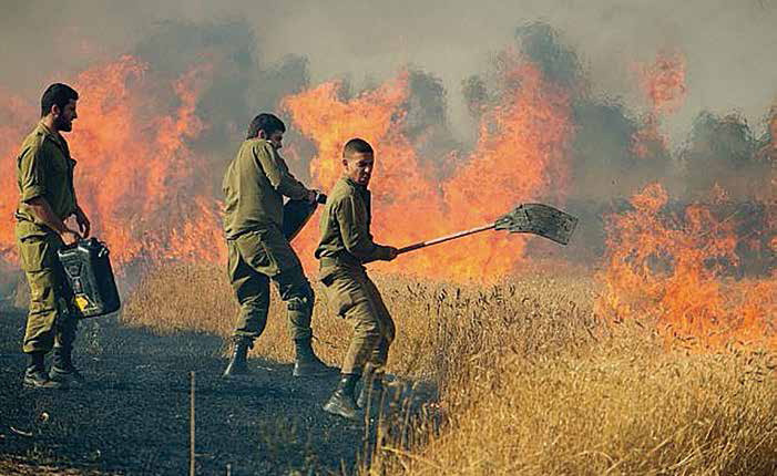 Israeli Soldiers Fighting Fires Soldiers battle flames that were started by hundreds of missiles fired from across the border in Gaza.