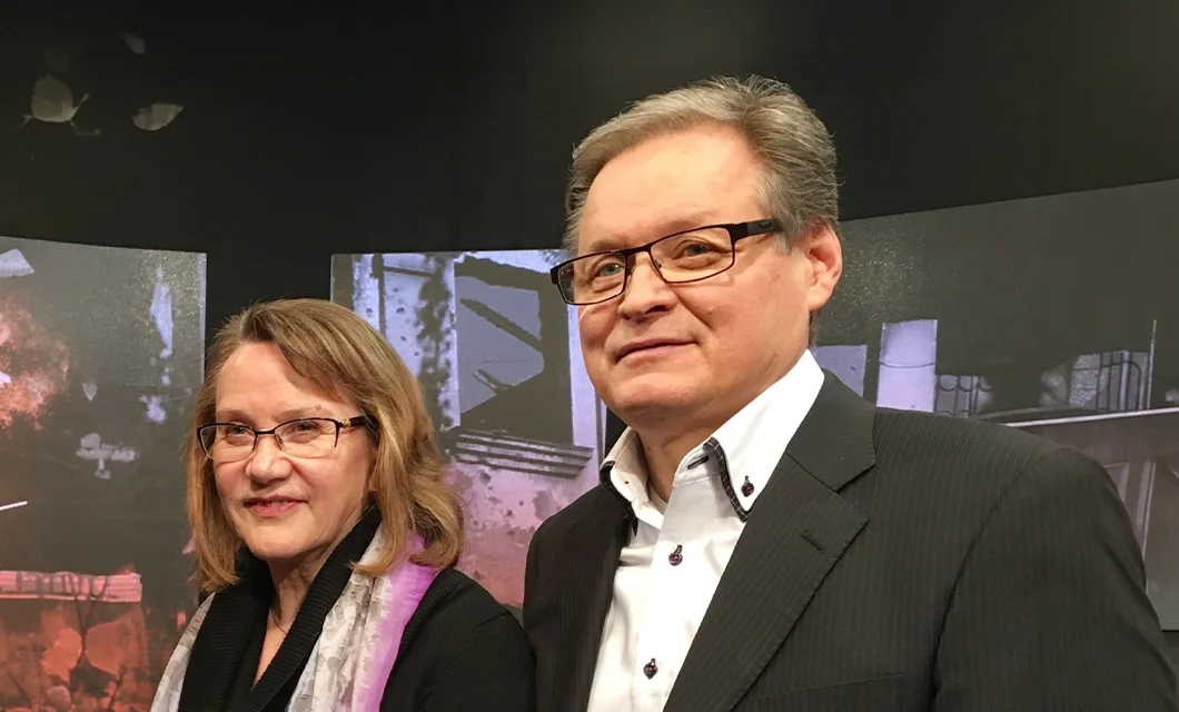 Hannu and Laura Haukka standing together in front of a media broadcast backdrop