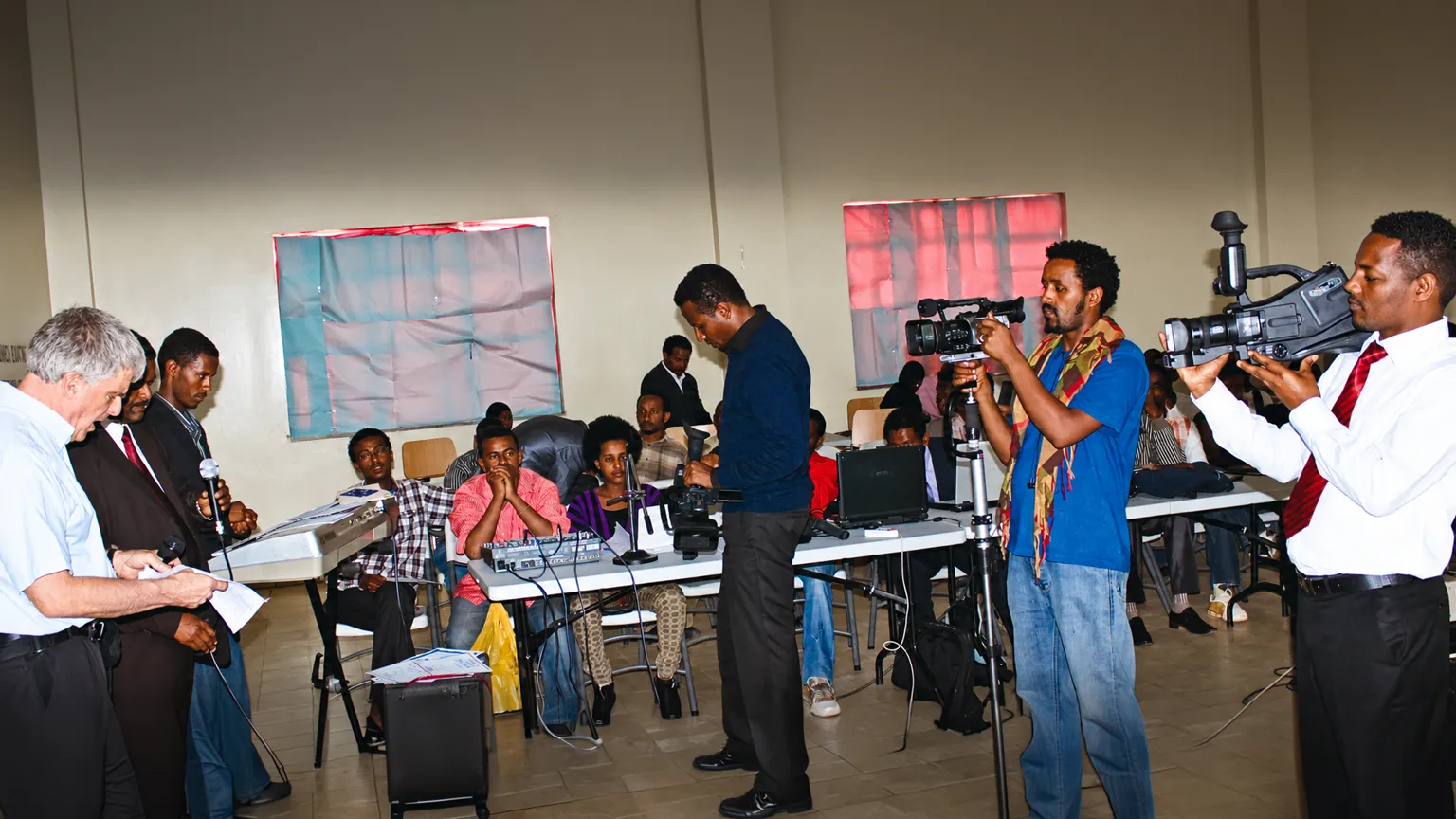Local media production team members prepare cameras and filming equipment during a Christian television production training session.