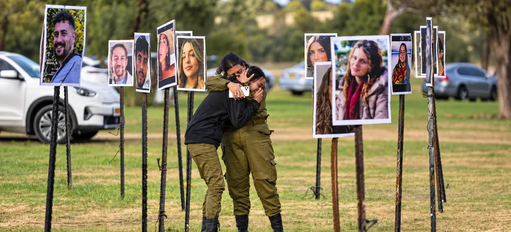 Two people embrace among portraits displayed at a memorial honoring victims of the October 7 attacks in Israel.