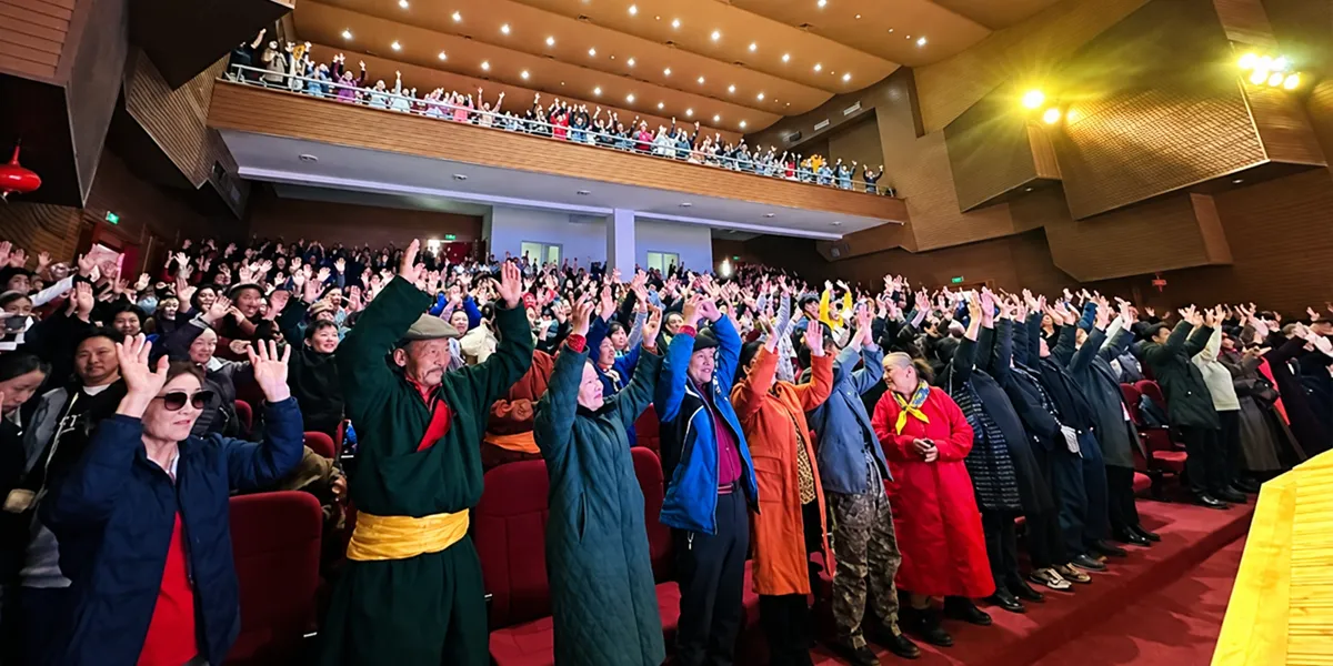 A large crowd raises their hands during a Christian gathering in an auditorium in Mongolia.
