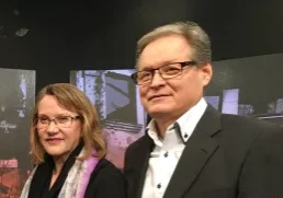 Hannu and Laura Haukka standing together in front of a media broadcast backdrop