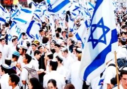 Crowd of people gathered outdoors waving Israeli flags during a public celebration or march.